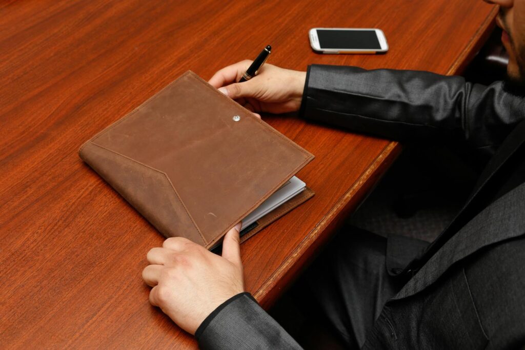 Person Holding Brown Leather Book